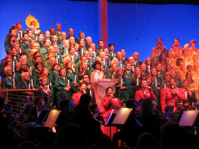 Disney Cast volunters in green robes make up the Christmas tree and the Voices of Liberty are in front in red and black